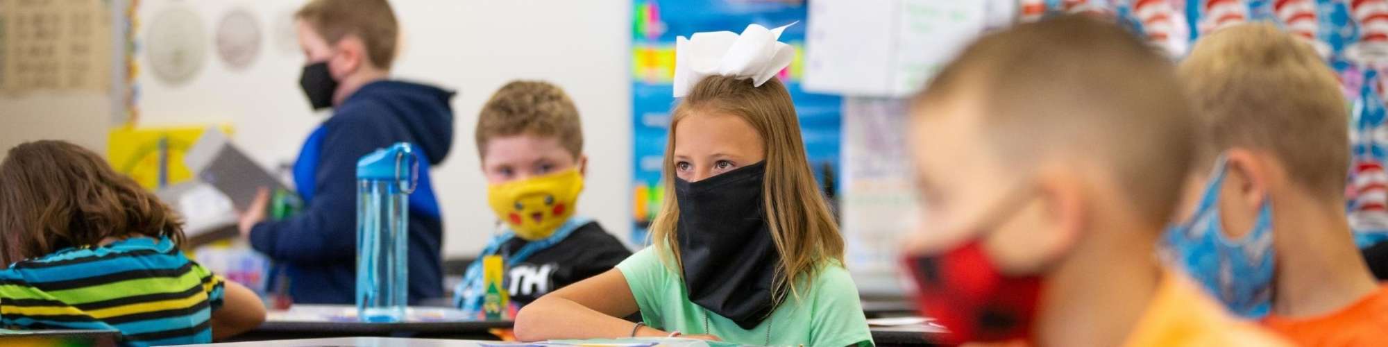 Students sitting at desks, wearing face masks.