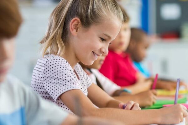 Student smiling while writing at desk