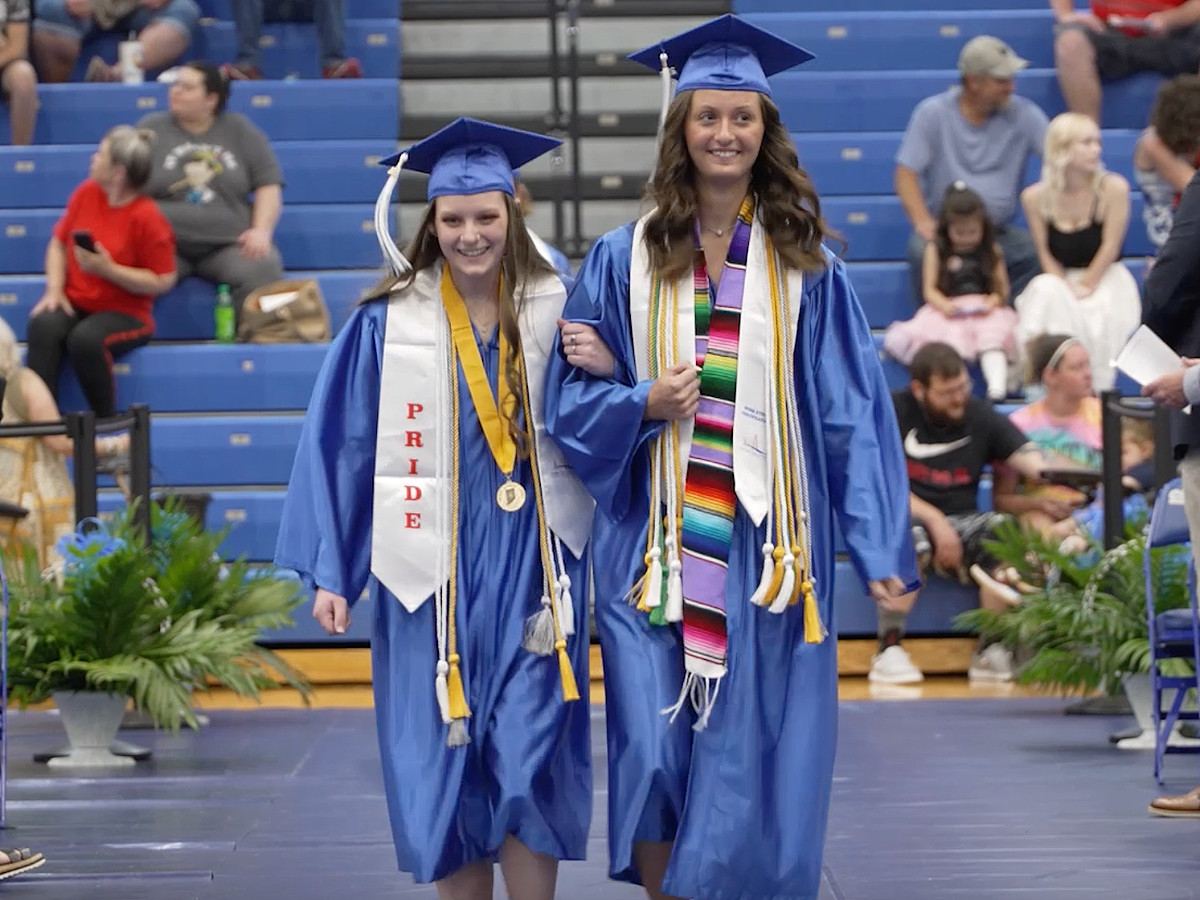 Two seniors walking into the graduation ceremony