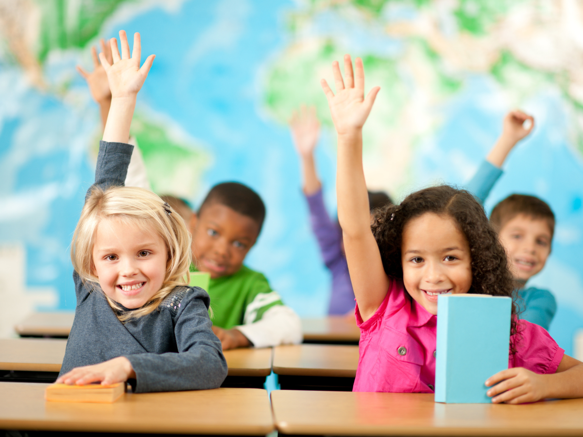 young students holding up hands in air